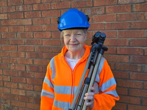 Sandra Davies in safety gear holding tripod