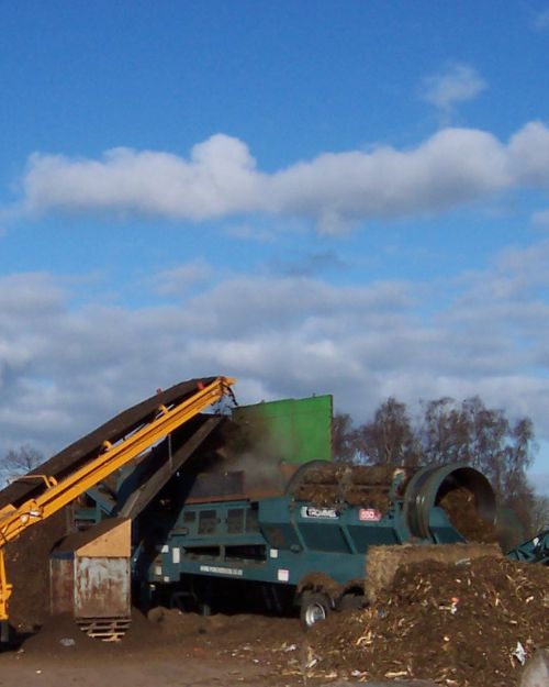 Machinery processing organic waste outdoors. bioaerosol hazard source from input and output.